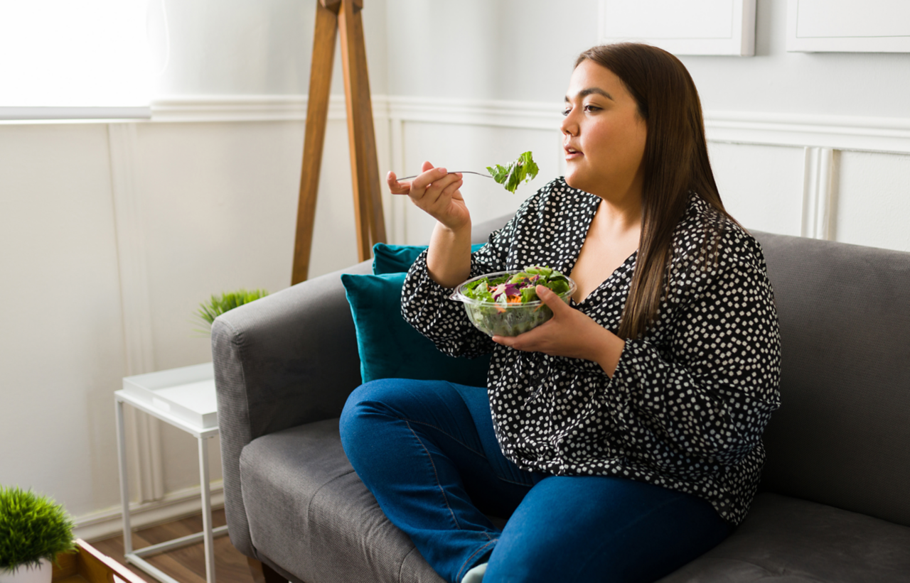 Woman on a sofa eating a salad